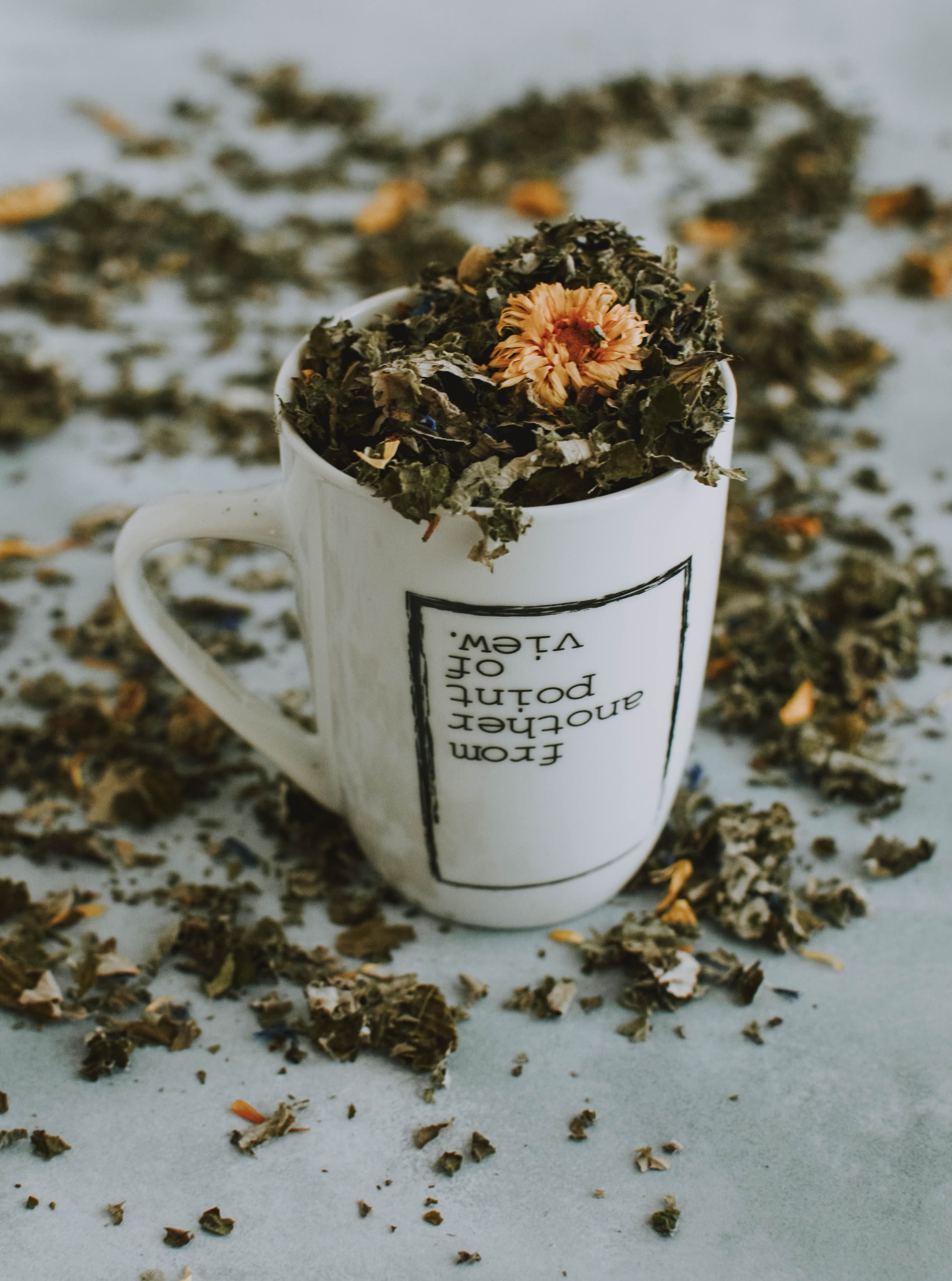 A mug overflowing with dried herbs and marigold petals